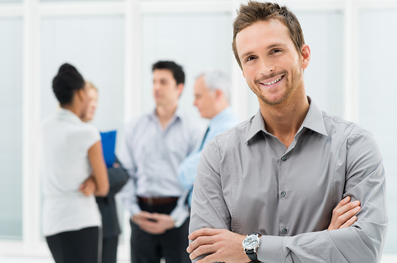 Portrait Of Young Handsome Businessman Smiling In Office